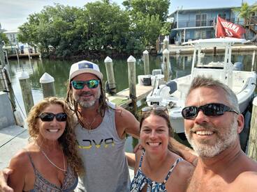 A cheerful group of friends poses for a selfie by their boat, capturing the excitement of a day on the water together.