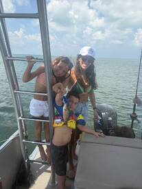 A joyful family enjoys a fishing trip on a boat, showcasing their catch while soaking up the sun — a perfect day on the water.