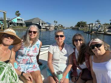 A cheerful group of friends enjoys a sunny day on a boat, cruising through a scenic canal — perfect for memorable outings and bonding experiences.