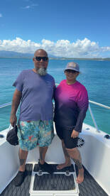 A cheerful couple poses on the deck of a boat, enjoying a sunny day on the ocean — perfect for memorable vacations and adventures at sea.