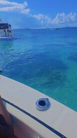 A close-up view from a boat with a person visible, showcasing the clear turquoise waters, but the main subject is unclear.