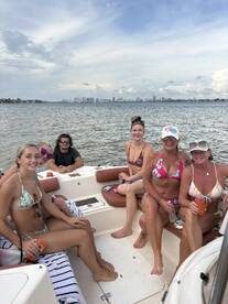 A lively group of friends enjoys a day on the water, relaxing on a boat with drinks in hand — perfect for summer outings and celebrations.