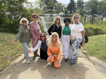 A joyful group of friends poses together by the water, capturing a moment of celebration and camaraderie before their boating adventure.