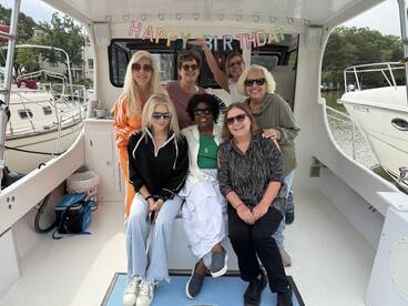 A joyful group celebrates a birthday aboard a boat, showcasing fun and camaraderie in a festive setting.