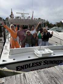 A lively group of friends celebrates a birthday aboard the 'Endless Summer' boat, showcasing joy and camaraderie in a festive atmosphere.