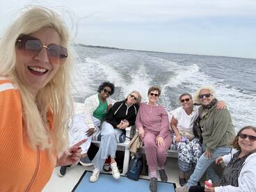A joyful group of friends enjoys a boat ride, capturing smiles and laughter as they cruise through the water — perfect for memorable outings and adventures.