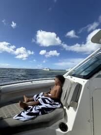 A young boy relaxes on the deck of a boat, enjoying the ocean view under a bright blue sky — a perfect moment of tranquility on the water.