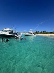 A lively group enjoys snorkeling in crystal-clear turquoise waters, surrounded by boats — a perfect day for aquatic adventures.