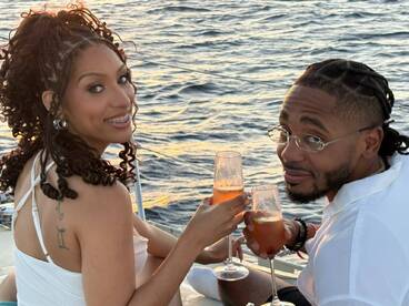 A couple enjoys cocktails while celebrating on a yacht, capturing the essence of a romantic sunset cruise.