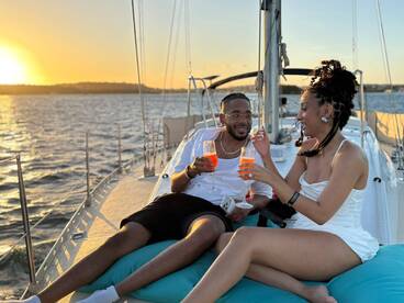 A couple enjoys cocktails on the deck of a yacht at sunset, creating a romantic atmosphere perfect for special celebrations.