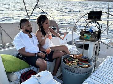 A couple enjoys cocktails and a delicious spread of food aboard a yacht, perfect for romantic outings or special celebrations on the water.