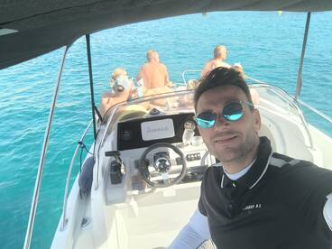 A group enjoys a sunny day on the water, with drinks in hand, showcasing the fun and camaraderie of a boat trip.