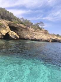 A picturesque view of a rocky coastline with clear turquoise waters, featuring swimmers enjoying the beautiful scenery — a perfect spot for a day of adventure and relaxation.