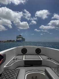 A scenic view from the deck of a boat, showcasing a large cruise ship in the distance against a vibrant sky — perfect for capturing the essence of a day on the water.