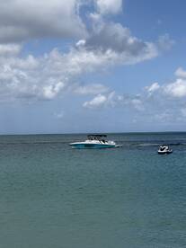 A thrilling scene of a jet ski rider enjoying the water alongside a powerboat, capturing the excitement of on-water activities in a beautiful coastal setting.