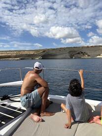 A family enjoys a scenic view from their boat, with a child pointing towards the coastline — a perfect moment of exploration and connection with nature.