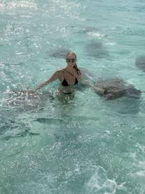 A woman interacts with stingrays in crystal-clear waters, showcasing an unforgettable wildlife experience in a tropical paradise.
