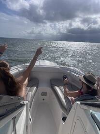 Two friends enjoy a fun day on the water, celebrating and taking in the beautiful ocean views from the bow of their boat.