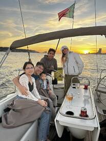 A joyful family enjoys a sunset sailing experience, complete with cocktails and cozy blankets, capturing the essence of togetherness on the water.