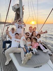 A joyful family poses for a group photo on a sailboat at sunset, capturing a memorable sailing experience filled with laughter and togetherness.