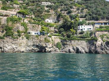 A picturesque view of coastal homes perched on cliffs, with a glimpse of a beach below — a stunning backdrop for a boating adventure along the shoreline.