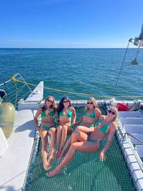 A group of friends relaxes on the netting of a catamaran, enjoying the sun and sea — perfect for a fun day out on the water.