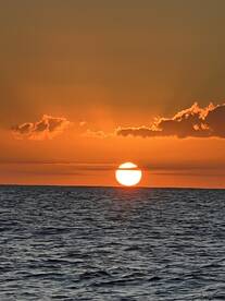 A stunning sunset over the ocean, casting vibrant hues across the sky — a perfect backdrop for evening boat cruises.