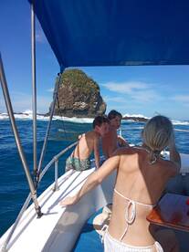 A group of children and an adult enjoy a scenic boat ride, with a rocky island in the background, capturing the essence of adventure on the water.