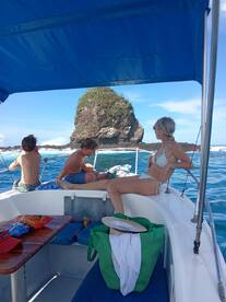A group enjoys a relaxing day on a boat, with a scenic rock formation in the background — perfect for ocean adventures and family outings.