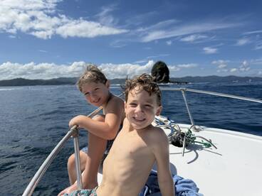 Two smiling children enjoy a sunny day on a boat, capturing the joy of ocean adventures and family fun.