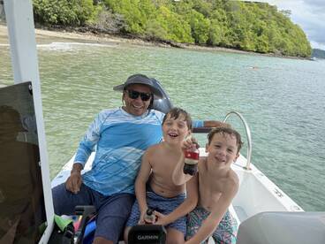 A joyful moment on a boat with two kids and an adult, enjoying drinks and smiles in a beautiful coastal setting — perfect for family adventures on the water.