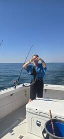 A woman proudly displays her catch while fishing on a boat, showcasing the excitement of a day out on the water.