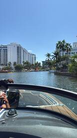 A scenic view from a boat navigating through a picturesque waterway lined with palm trees and city buildings, capturing the essence of a vibrant boating experience.