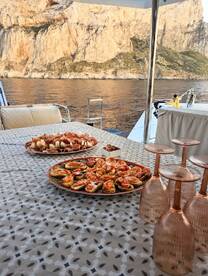A beautifully arranged spread of charcuterie and appetizers on a boat table, perfect for enjoying gourmet meals while taking in stunning coastal views.