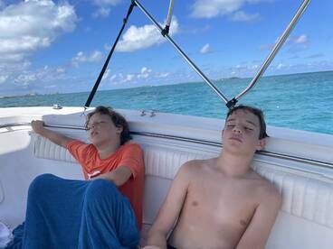 Two boys relax on a boat, enjoying the serene ocean views — a perfect moment of calm during a fun day on the water.