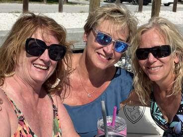 Three friends enjoy a sunny day together, sipping cocktails and celebrating life — perfect for memorable outings on the water.