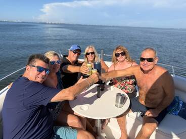 A cheerful group of friends toasts with drinks aboard a pontoon boat, enjoying a perfect day on the water — ideal for celebrations and gatherings.