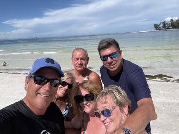 A cheerful group of friends poses for a selfie on the beach, capturing a fun day in the sun — perfect for memorable beach outings and celebrations.
