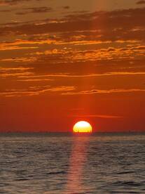 A breathtaking sunset over the ocean, casting vibrant orange hues across the sky and water — a perfect backdrop for evening boat trips or romantic getaways.