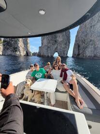 A joyful group poses for a photo on a boat with stunning rock formations in the background, capturing a memorable moment during their adventure.