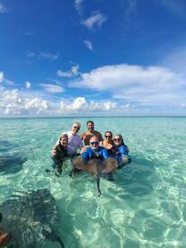 A group of friends enjoys a memorable experience swimming with stingrays in crystal-clear waters, showcasing the thrill of wildlife encounters in a tropical paradise.