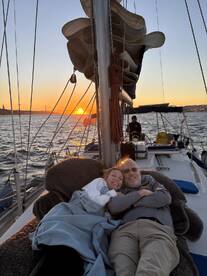 A couple enjoys a cozy moment on a sailboat at sunset, wrapped in blankets and celebrating the beauty of the evening — perfect for romantic getaways on the water.