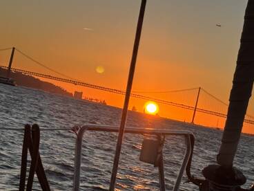 A stunning sunset view from a boat, showcasing the silhouette of a bridge against the vibrant sky — perfect for capturing the beauty of evening cruises.