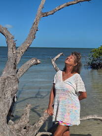 A woman enjoys a sunny day at the beach, surrounded by beautiful scenery and a serene ocean backdrop — perfect for capturing joyful moments in nature.