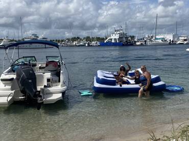 A lively group enjoys a fun day at the beach on an inflatable float, showcasing the perfect blend of relaxation and celebration in the sun.