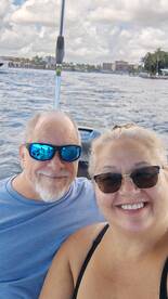 A happy couple enjoys a sunny day on the water, capturing a selfie while boating — perfect for memorable outings and adventures.