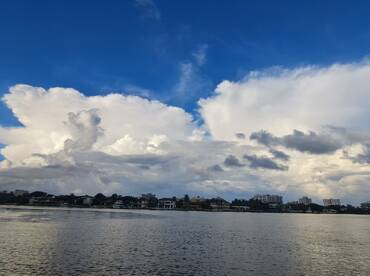 A scenic view of clouds over a waterfront, capturing the beauty of nature and the tranquility of the water.