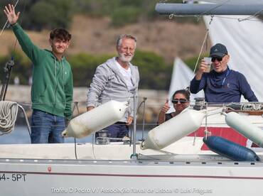 A cheerful group aboard a sailboat waves and celebrates, capturing the joy of sailing adventures together.
