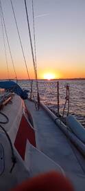 A serene sunset view from the deck of a sailboat, showcasing the tranquil waters and vibrant colors of the evening sky — perfect for romantic sailing experiences.
