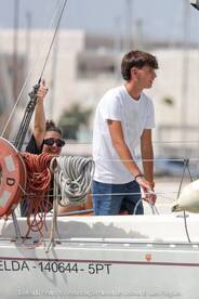 A young man and a woman enjoy their time on a sailboat, showcasing the excitement of sailing and camaraderie on the water.